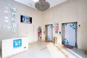A hotel lobby with a reception desk, a chandelier, and two elevators. - Weiyesi Hotel (Shenzhen)