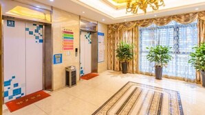 A hotel lobby with a chandelier, potted plants, a patterned rug, and a reception desk. - Weiyesi Hotel (Shenzhen)