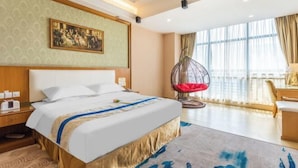A hotel room with a large bed, a hanging chair, a painting on the wall, and a view of the city through large windows. - Weiyesi Hotel (Shenzhen)