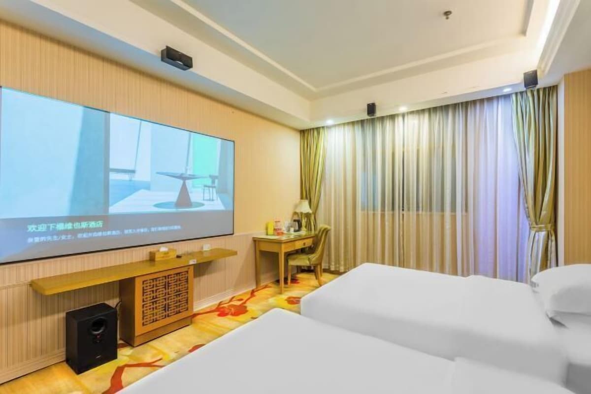 A hotel room with a bed, a desk, a chair, a television, and a curtain.