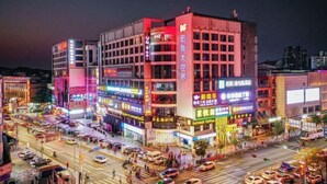 A multi-story building with illuminated signage and a busy street scene at night. - Weiyesi Hotel (Shenzhen)