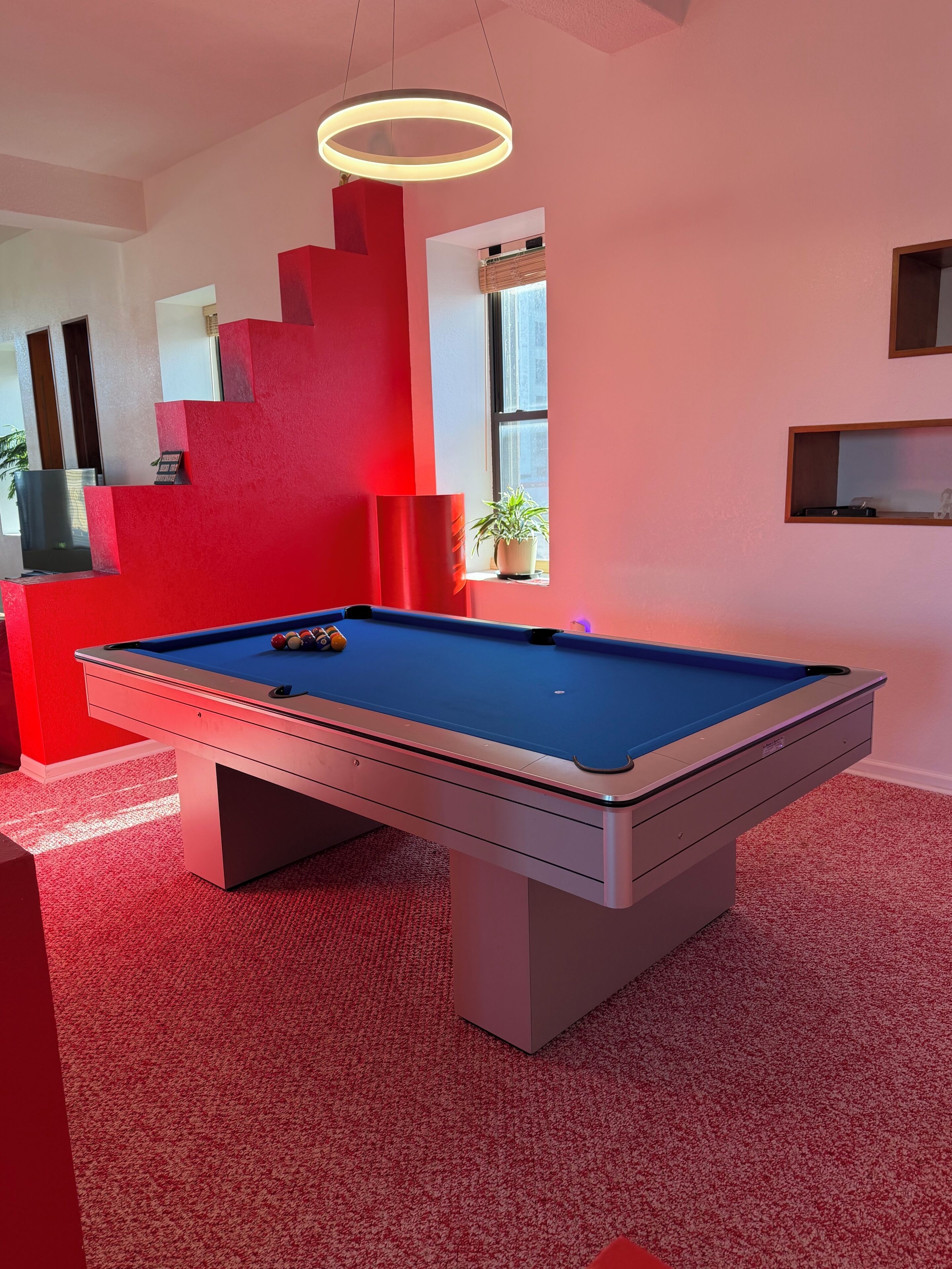 A pool table in a room with red walls and a modern design.