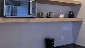 A kitchen with a microwave, coffee maker, and a toaster on the counter.