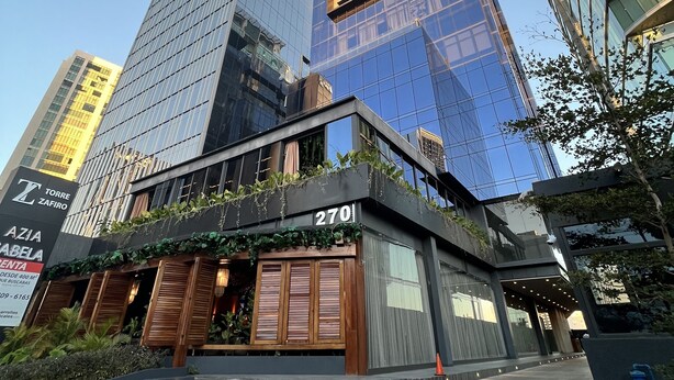 A modern building with a glass facade, a visible entrance with wooden shutters, and a sign indicating the address as 270.