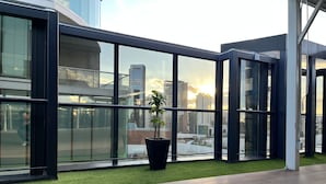 A modern interior with large windows, a potted plant, and a wooden deck.