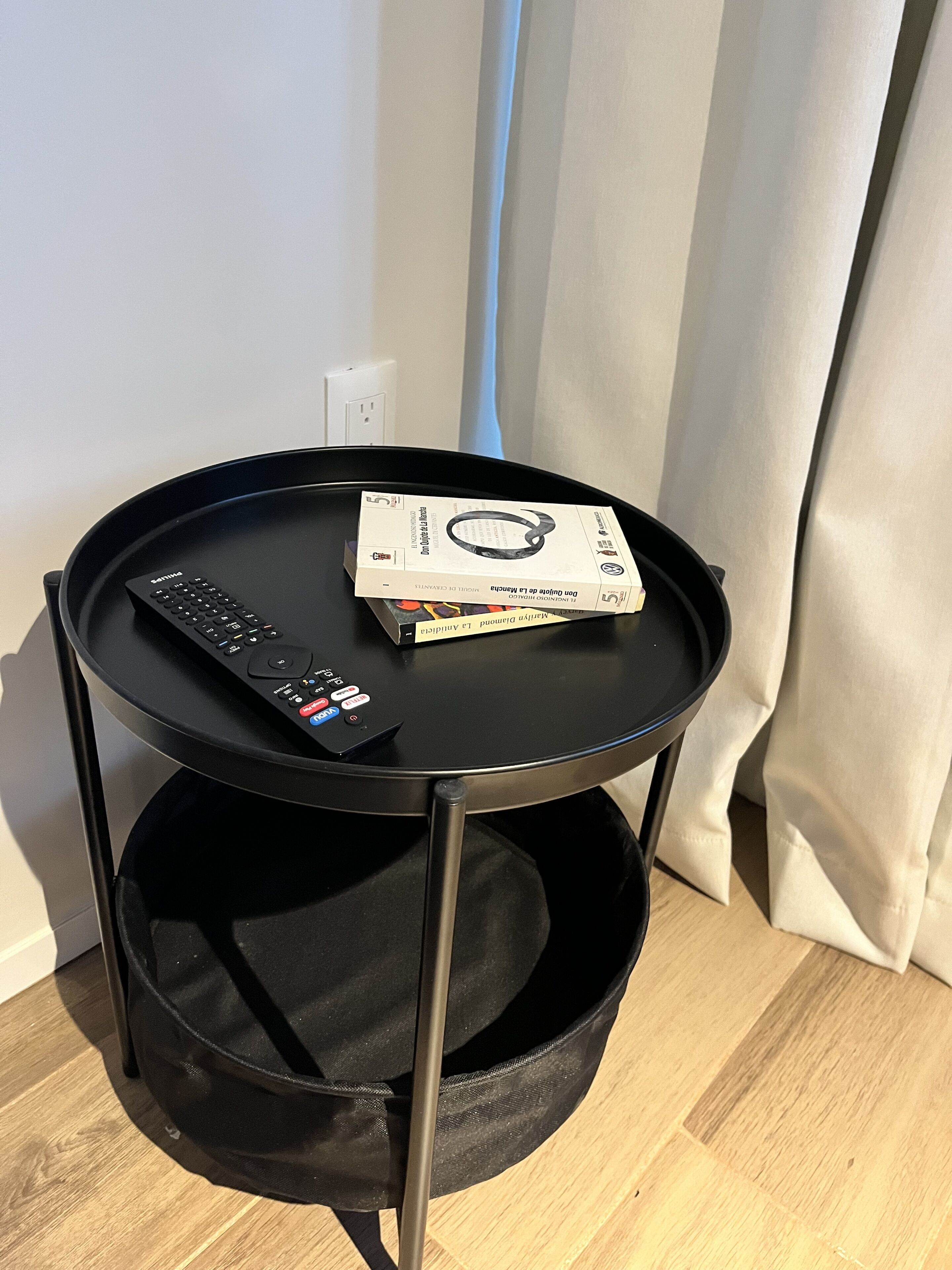 A small black side table with a remote control and a book on it.