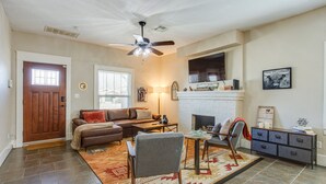 A spacious living room with a fireplace, a ceiling fan, and a large window. - Chic Lawton Home, 5 Mins to Fort Sill! (Lawton)