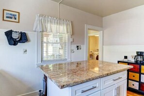 Enjoy meals in this kitchen with a granite countertop, white cabinetry, and a window overlooking the surrounding area.