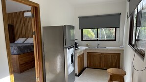 Een kleine keuken met een koelkast, wastafel en houten keukenkastjes.
