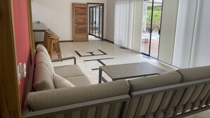 Een ruime woonkamer met een bank, een salontafel en een houten deur naar een balkon.