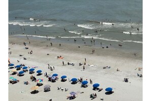 Ein Strand mit vielen Sonnenschirmen und Menschen, die das Wasser genießen.