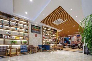 A modern interior with a reception area, seating, and a wall of shelves with various items. - Home Inn Huaxuan Select Hotel (Weihai High-speed Railway Station Hanlefang Branch) (Weihai)