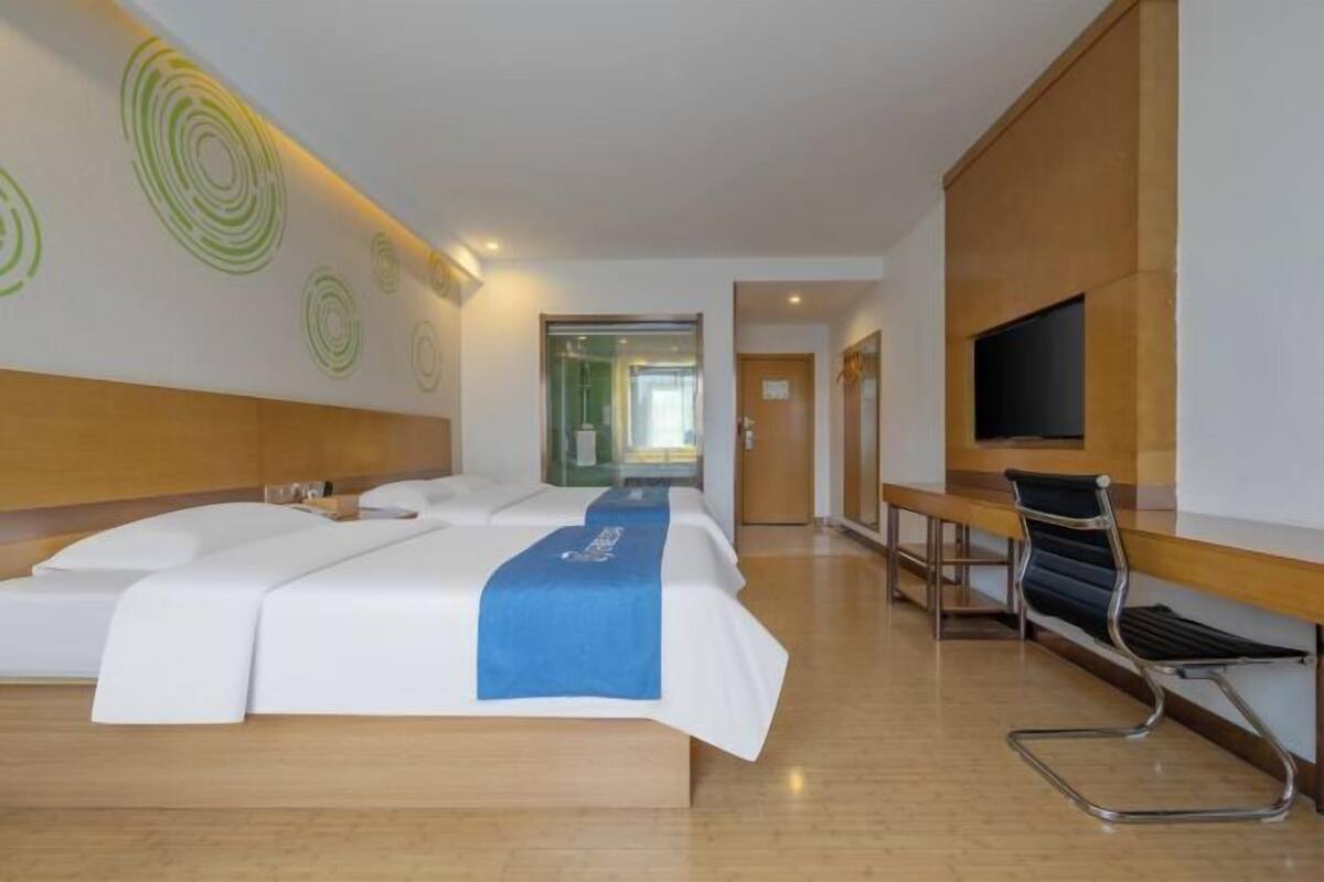 A hotel room with a large bed, a desk, a chair, and a TV.