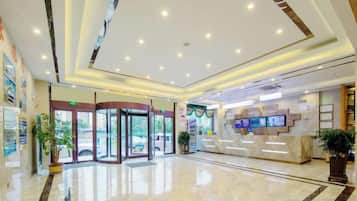 Una hall d'albergo con reception, ingresso con porta in vetro e pavimento in marmo.