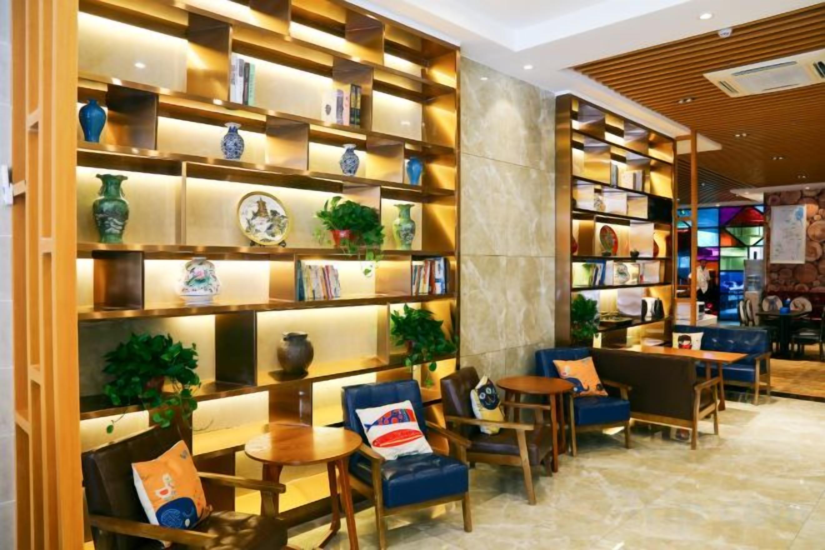 A hotel lobby with a wooden bookshelf, seating area, and a marble floor.