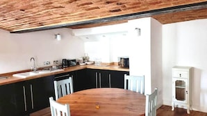 A kitchen with a wooden table and chairs, a sink, and a white cabinet. - Inviting 1-bed Apartment in Banbury (Banbury)
