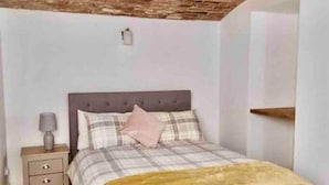 A bedroom with a bed, a nightstand, a lamp, and a brick ceiling. - Inviting 1-bed Apartment in Banbury (Banbury)