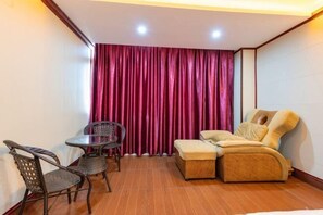 A room with a sofa, a small table, and two chairs. - Zhongshan Guanlong Hotel (Zhongshan)