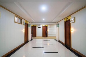 A hotel corridor with doors, a light fixture, and a tiled floor. - Zhongshan Guanlong Hotel (Zhongshan)