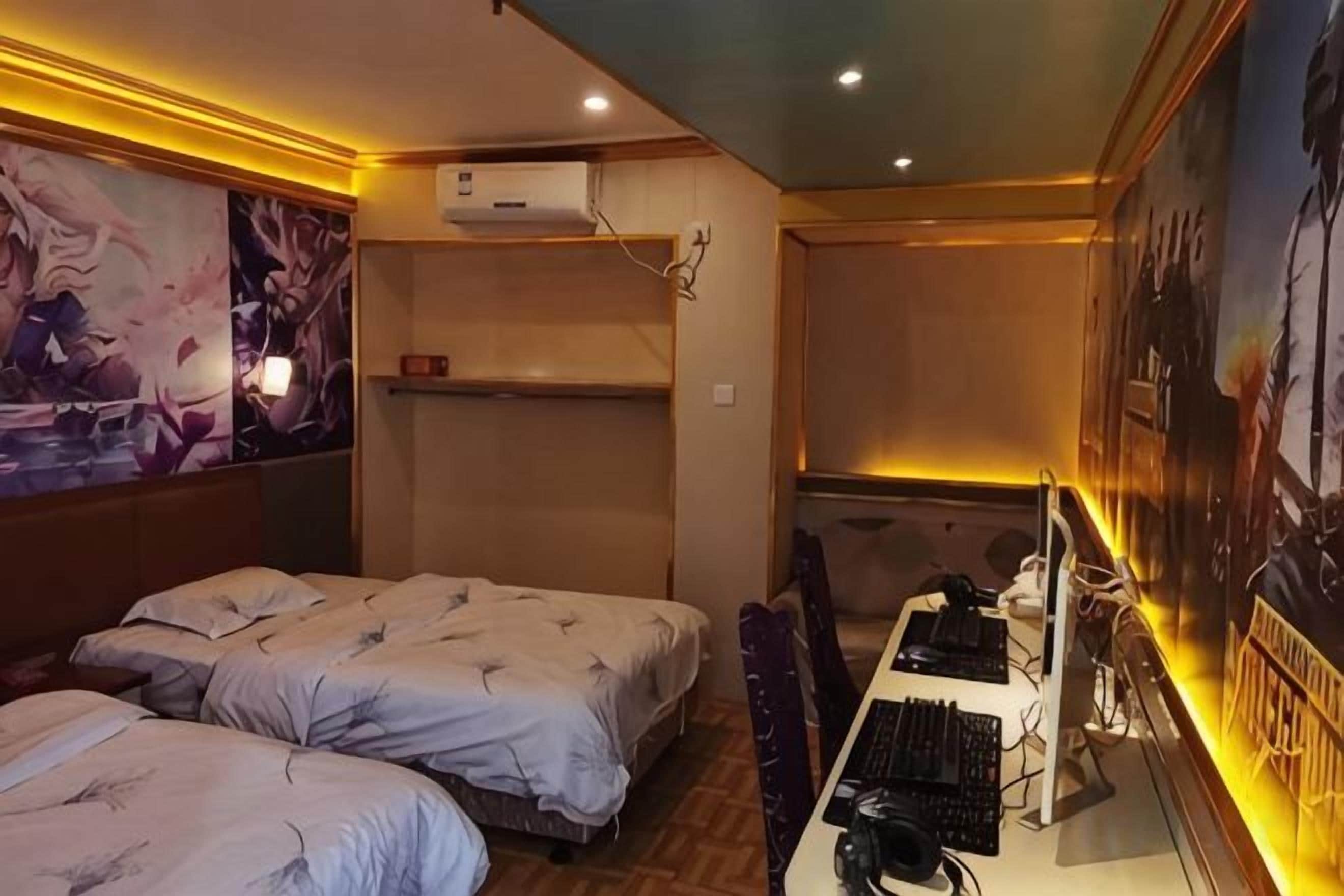 Habitación de hotel con dos camas, un escritorio con computadora y obras de arte en las paredes.