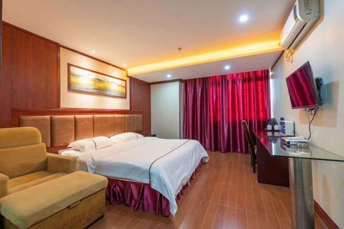 A hotel room with a bed, a sofa, a desk, and a TV.