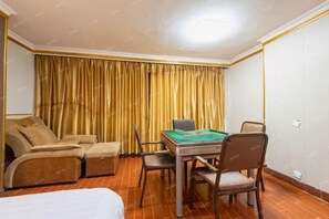 A hotel room with a sofa, a table with a board game, and a bed. - Zhongshan Guanlong Hotel (Zhongshan)