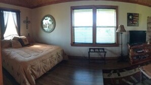 A cozy living room with a fireplace, a large window, and a dining area. - Country Cabin  10 miles from Round Top (Burton)
