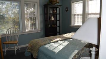 Une chambre à coucher avec un lit, une chaise, une table de chevet et une fenêtre avec des stores.