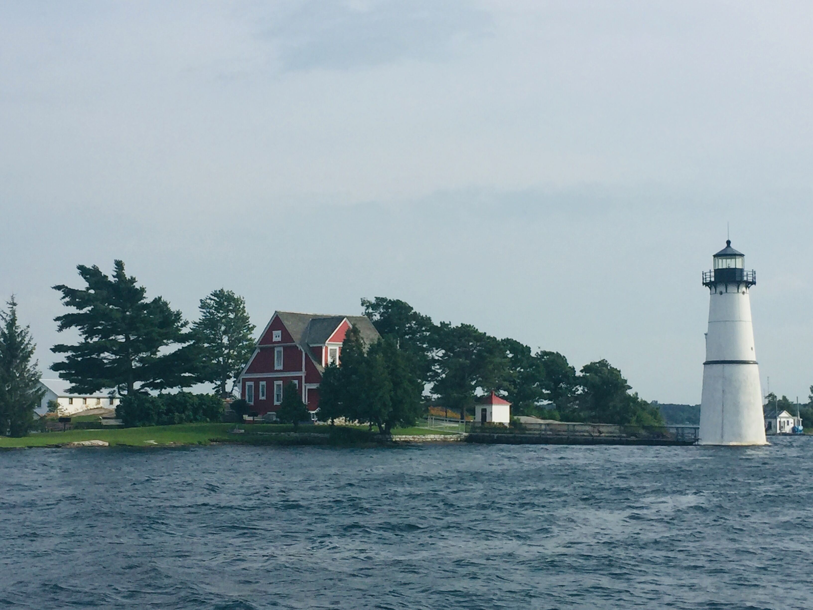 A lighthouse and a red house by the water.