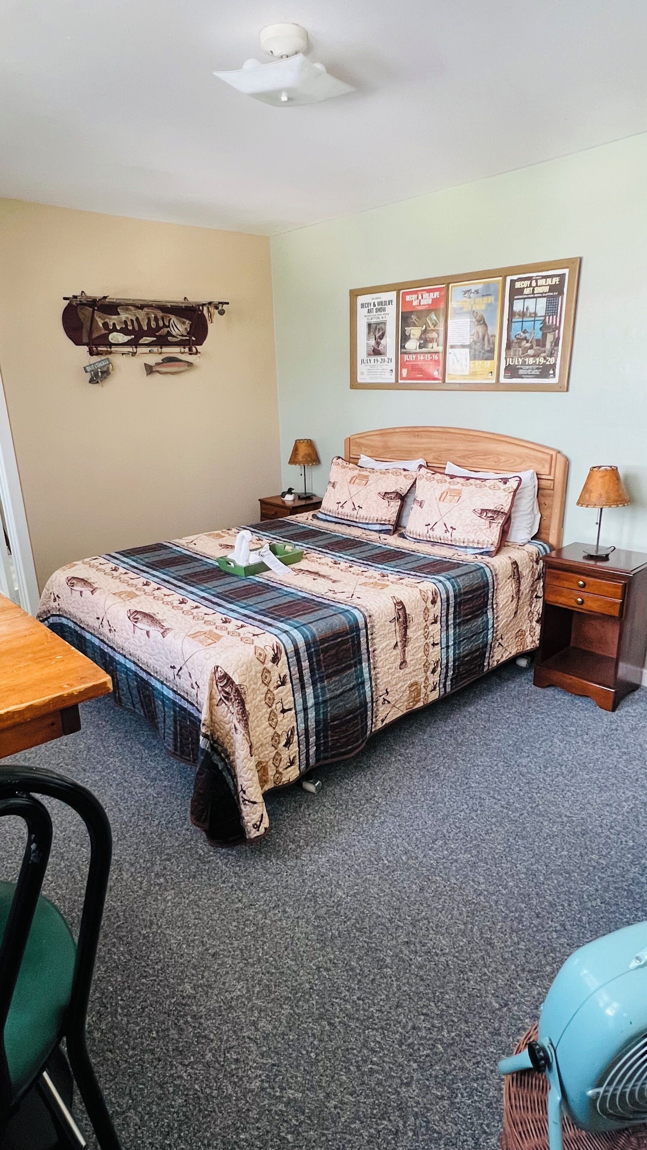 Un dormitorio ordenado con cama, mesitas de noche, un escritorio y una silla.
