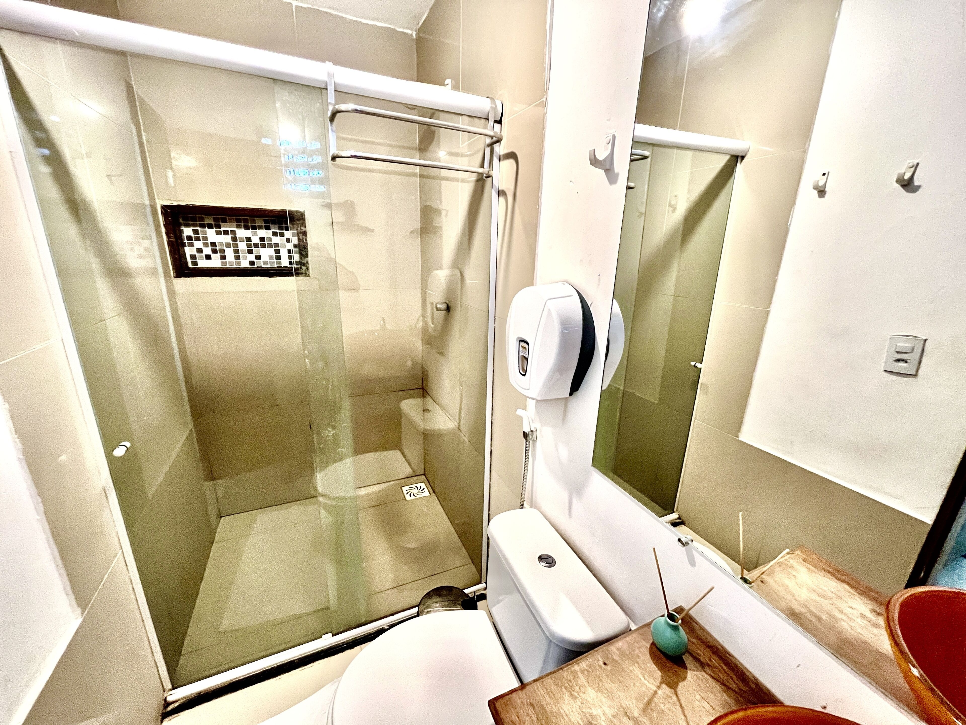 A modern bathroom with a glass-enclosed shower, a toilet, and a hand dryer.