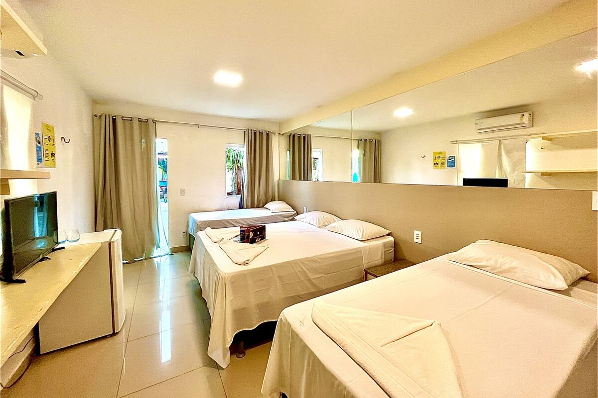 Une chambre d’hôtel avec deux lits, une télévision et une salle de bain visible à travers un rideau.