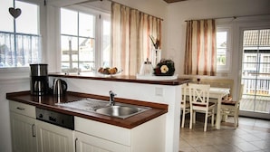 A kitchen with a wooden countertop, stainless steel sink, and a dishwasher. There is a dining area with a white table and chairs. - FH „Kajüte“81m², 4 Pers. im Marinapark Scharmützelsee, Sauna, Whirlpool, Kamin (Wendisch Rietz Siedlung)