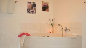 A large freestanding bathtub with a towel draped over it, a small vase with flowers, and a candle on the floor. - FH „Kajüte“81m², 4 Pers. im Marinapark Scharmützelsee, Sauna, Whirlpool, Kamin (Wendisch Rietz Siedlung)