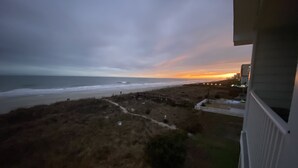 A coastal view from a balcony overlooking a beach with a path leading to the shore. - Ocean front at the chateau (North Myrtle beach)