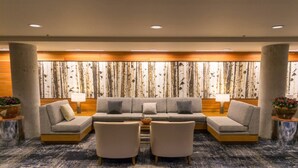 A modern lobby with a sectional sofa, two armchairs, a coffee table, and a large wall mural.