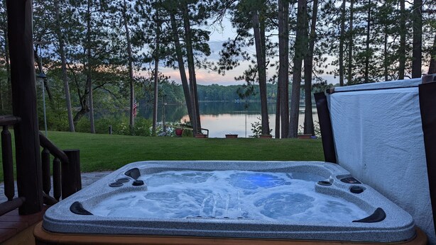A hot tub with a view of a lake and trees.