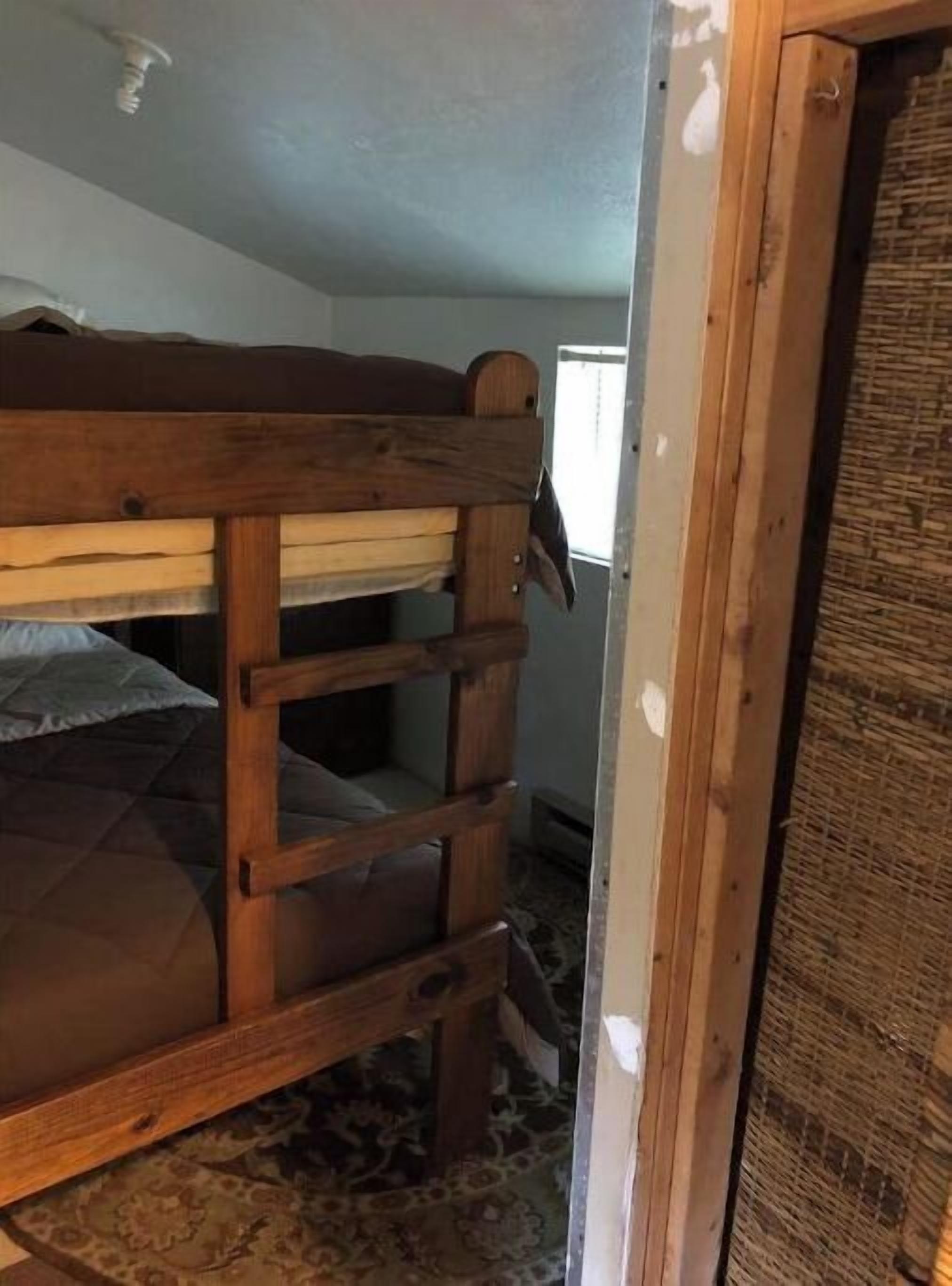 Un lit superposé dans une chambre avec un tapis à motifs et une fenêtre.