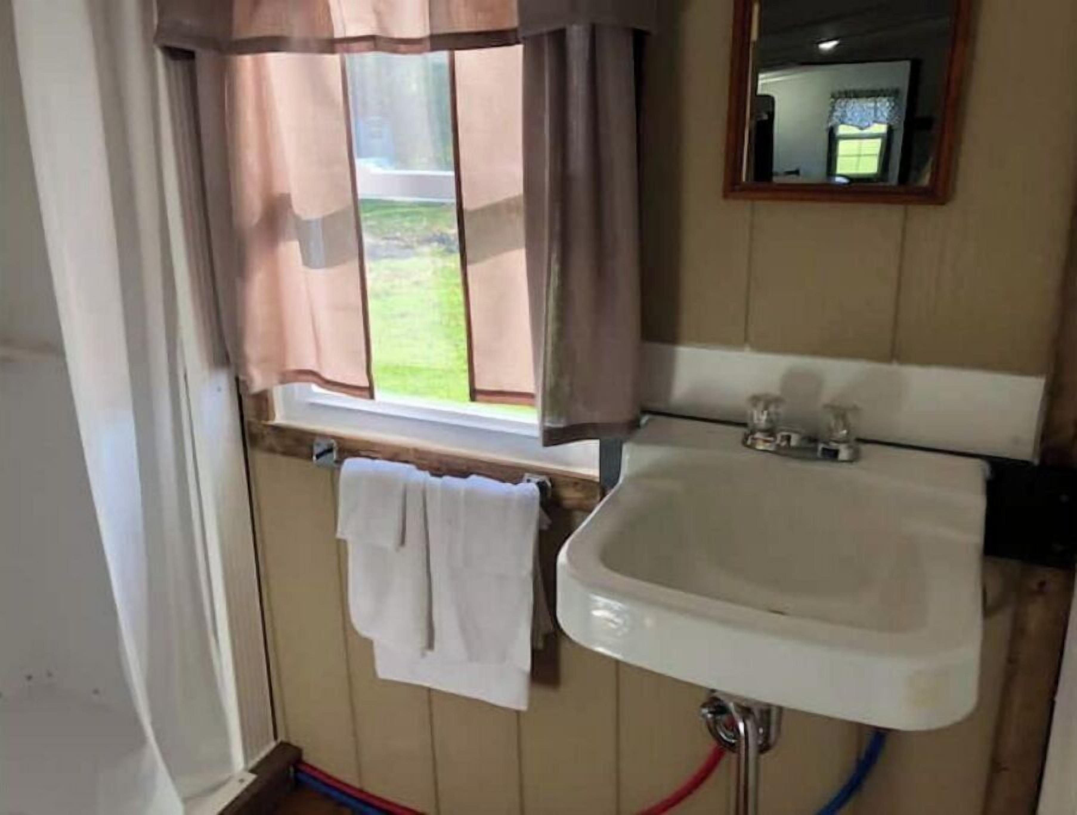 A bathroom with a window, a sink, and a towel hanging on the wall.