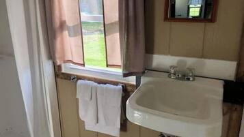 A bathroom with a window, a sink, and a towel hanging on the wall.