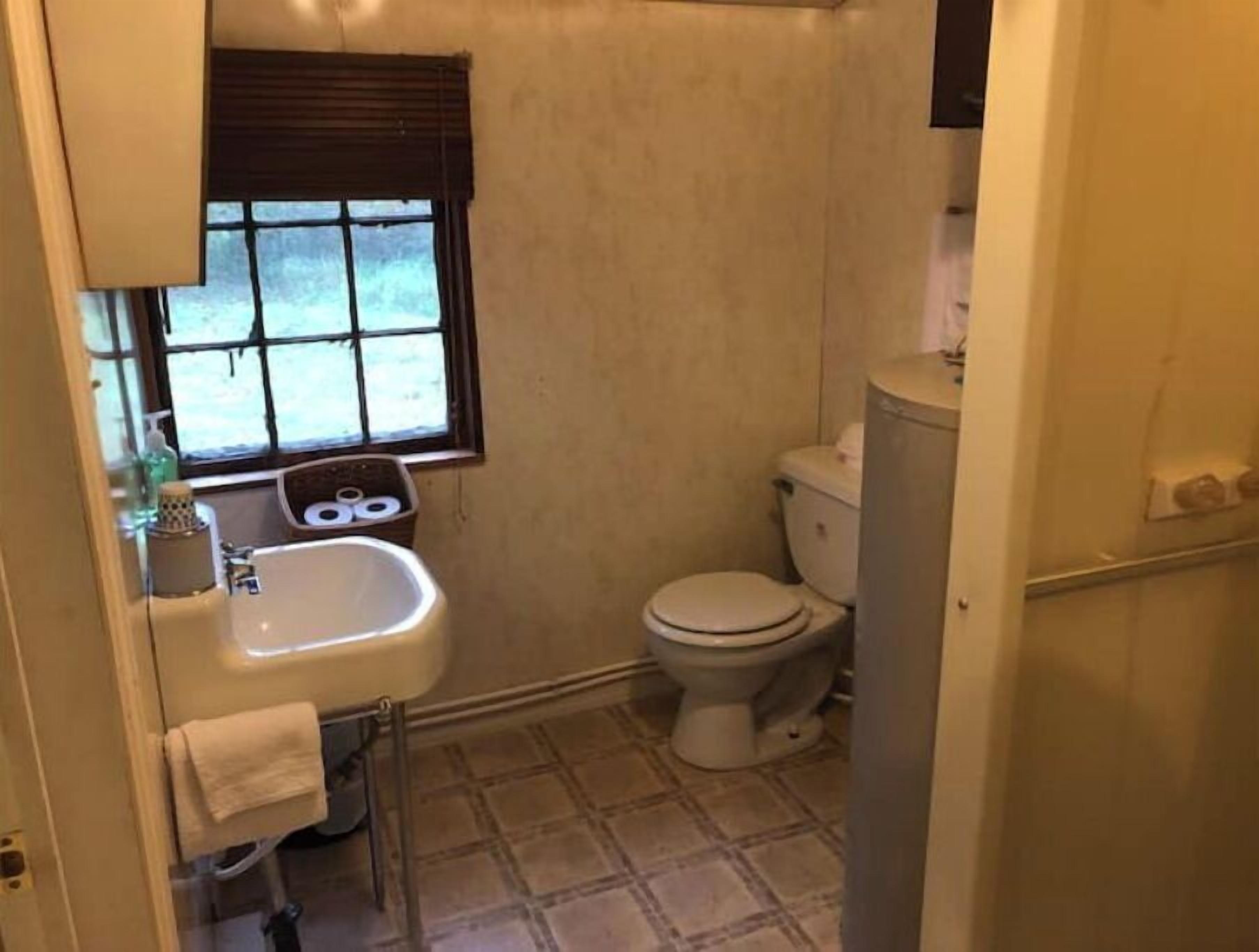 Ein kleines, kompaktes Badezimmer mit Toilette, Waschbecken und Fenster.