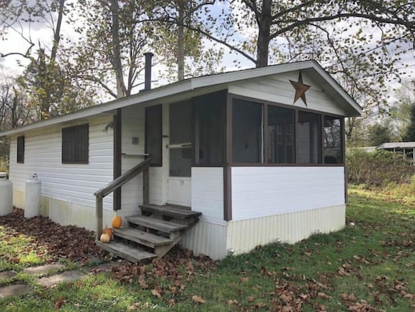 Une petite maison mobile d’un seul étage, dotée d’un porche et d’une décoration en forme d’étoile sur le toit.
