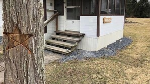 Ein kleines, eingeschossiges Gebäude mit einer Veranda und einer Holztreppe, die zum Eingang führt.