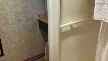 A bathroom with a shower, tiled walls, and wooden flooring.