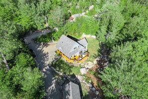 Une maison avec une terrasse et un petit étang.