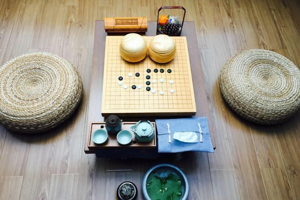Tatami-mattoilla päällystetty huone, jossa on go-lauta, teekuppisetti ja punottuja jakkaroita.