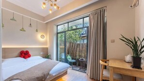A bedroom with a bed, a wooden desk, and a window with curtains. - wuginggu Hostel (Hangzhou)