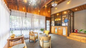 A cozy interior with wooden accents, a reception desk, seating area, and large windows. - wuginggu Hostel (Hangzhou)