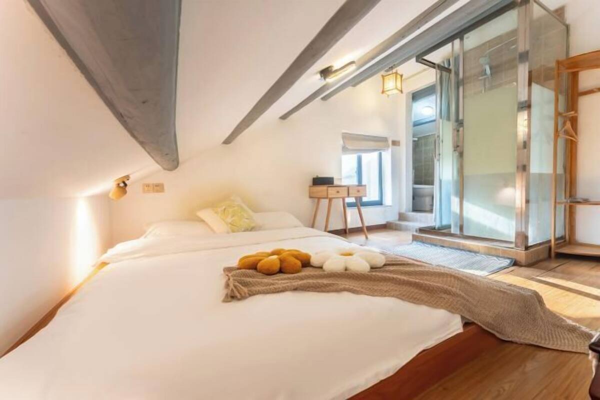 A bedroom with a bed, a bedside table, a lamp, and a window.