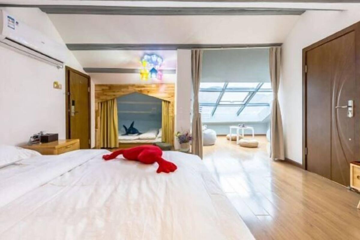 A hotel room with a large bed, a wooden headboard, a skylight, and a view of the outdoors.